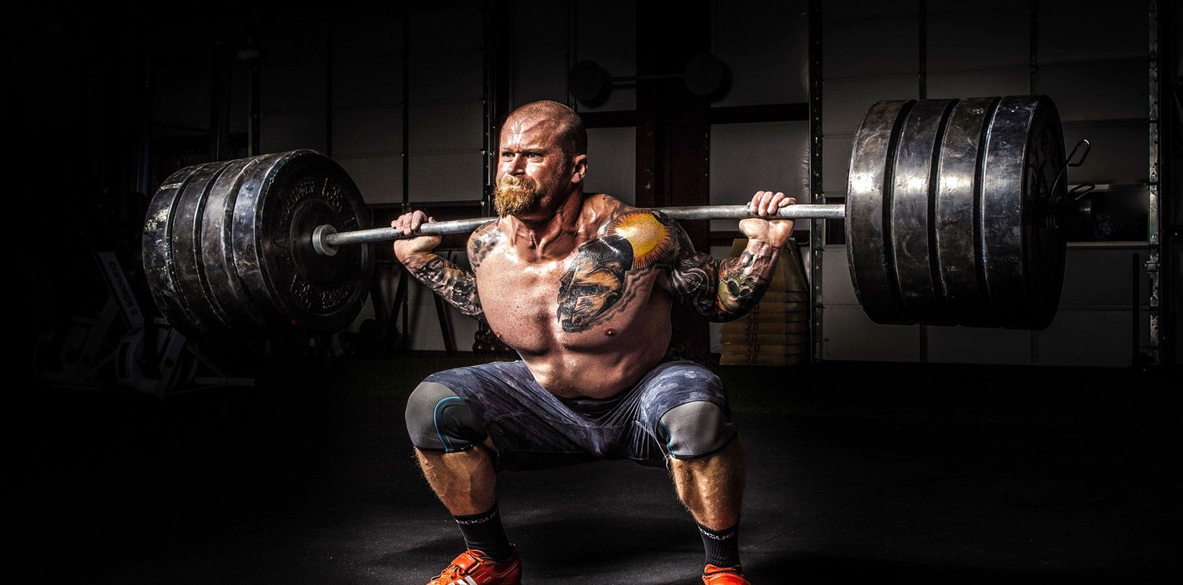 Athlete squatting a heavy barbell in a dark gym